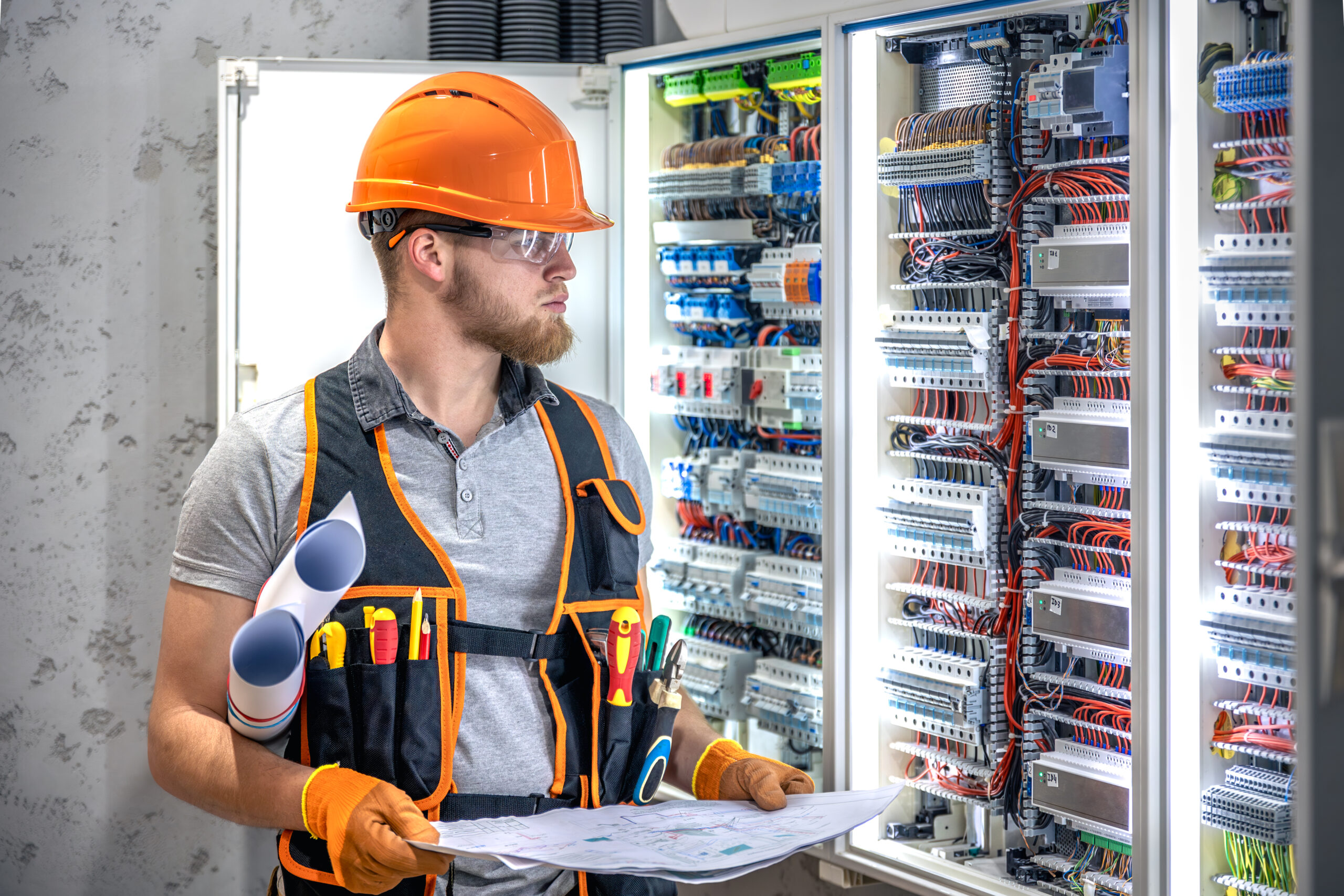 Male electrician working in electrical panel. Male electrician in overalls.